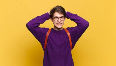 Genç öğrenci kendini stresli, endişeli, endişeli ya da korkmuş hissediyor. Elleri başının üstünde, hatayla panikliyor.