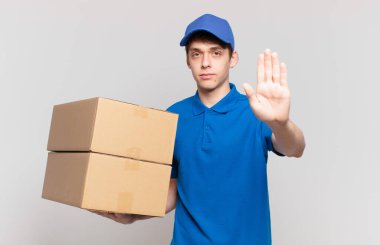 Genç paket teslimatçısı çocuk ciddi, sert, hoşnutsuz ve kızgın görünüyor.