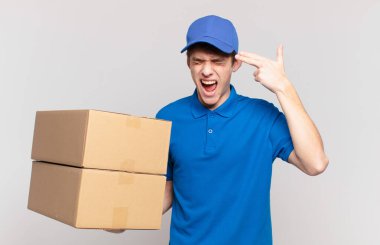 Genç paket teslimatçısı mutsuz ve stresli görünüyor, intihar jesti elle silah işareti yapıyor, kafasını işaret ediyor.