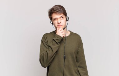 Genç pazarlamacı düşünüyor, kuşkulu ve şaşkın hissediyor, farklı seçeneklerle, hangi kararı vereceğini merak ediyor.