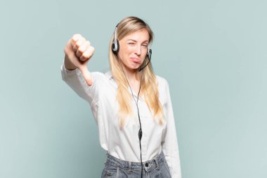 Genç sarışın tele pazarlamacı kadın kızgın, sinirli, hayal kırıklığına uğramış ya da hoşnutsuz, ciddi bir bakışla başparmağını kaldırıyor.