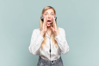 Genç sarışın tele pazarlamacı kadın mutlu, heyecanlı ve pozitif hissediyor, elleri ağızın yanında bağırıyor, bağırıyor