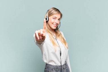 Genç sarışın tele pazarlamacı kadın gururla gülümsüyor ve bir numaralı pozunu başarıyla veriyor, kendini lider gibi hissediyor.