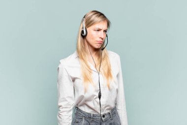 Genç sarışın tele pazarlamacı kadın üzgün, üzgün ya da kızgın ve olumsuz bir tavır takınıyor, anlaşmazlık içinde kaşlarını çatıyor.