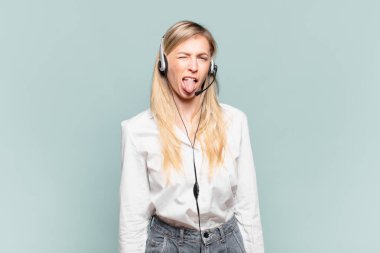 Genç sarışın tele pazarlamacı kadın iğrenmiş ve rahatsız olmuş hissediyor, dilini dışarı çıkarıyor, iğrenç ve iğrenç bir şeyden hoşlanmıyor.