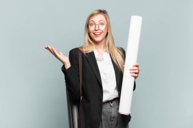 Genç mimar kadın kendini mutlu, şaşırmış ve neşeli hissediyor. Pozitif bir tavırla gülümsüyor. Bir çözüm ya da fikir buluyor.