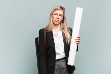 young architect woman feeling puzzled and confused, with a dumb, stunned expression looking at something unexpected