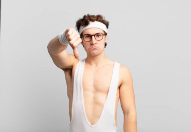 Huysuz, sinirli, sinirli, hayal kırıklığına uğramış ya da canı sıkkın bir sporcu, ciddi bir bakışla başparmağını kaldırıyor.