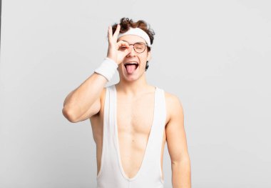 humorous sport man smiling happily with funny face, joking and looking through peephole, spying on secrets