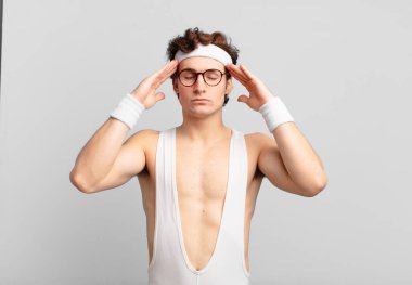 humorous sport man looking concentrated, thoughtful and inspired, brainstorming and imagining with hands on forehead