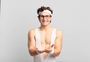 humorous sport man smiling happily with friendly, confident, positive look, offering and showing an object or concept