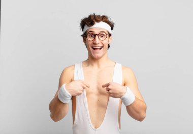 humorous sport man feeling happy, surprised and proud, pointing to self with an excited, amazed look