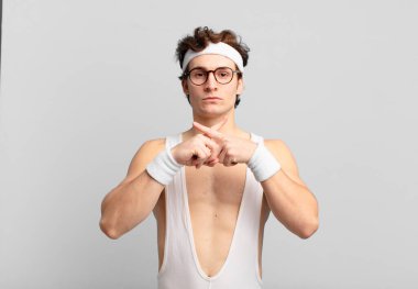 humorous sport man looking serious and displeased with both fingers crossed up front in rejection, asking for silence
