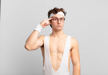 humorous sport man feeling confused and puzzled, showing you are insane, crazy or out of your mind
