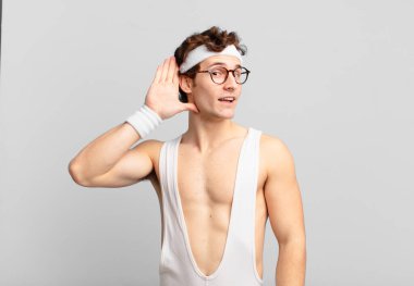 humorous sport man smiling, looking curiously to the side, trying to listen to gossip or overhearing a secret