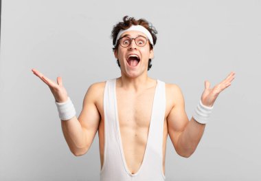 humorous sport man feeling happy, amazed, lucky and surprised, celebrating victory with both hands up in the air