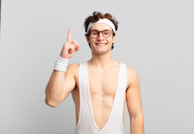 humorous sport man smiling cheerfully and happily, pointing upwards with one hand to copy space