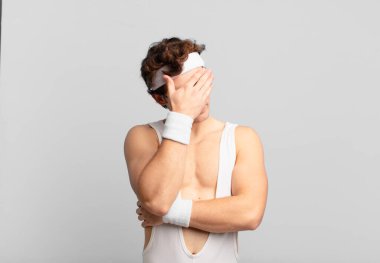 humorous sport man looking stressed, ashamed or upset, with a headache, covering face with hand