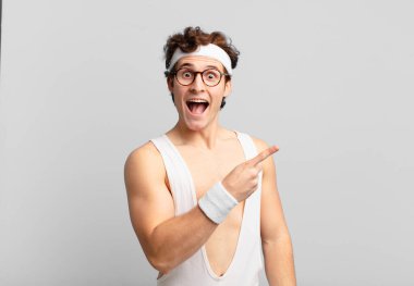 humorous sport man looking excited and surprised pointing to the side and upwards to copy space