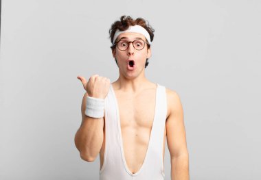 humorous sport man looking astonished in disbelief, pointing at object on the side and saying wow, unbelievable