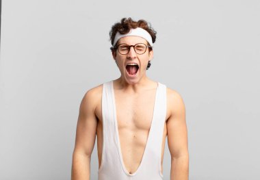 humorous sport man shouting aggressively, looking very angry, frustrated, outraged or annoyed, screaming no