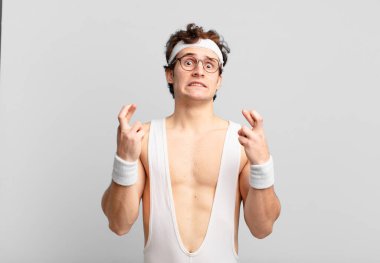 humorous sport man crossing fingers anxiously and hoping for good luck with a worried look