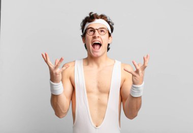 Komik sporcu adam öfkeyle bağırıyor, stresli hissediyor ve ellerini havaya kaldırıp 