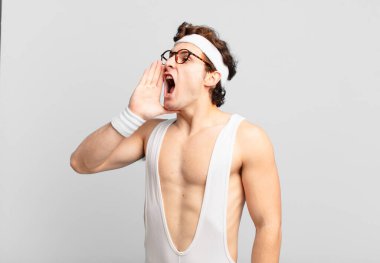 humorous sport man yelling loudly and angrily to copy space on the side, with hand next to mouth