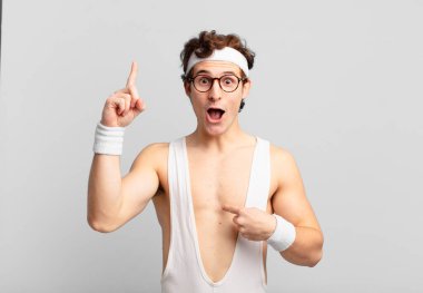 humorous sport man feeling proud and surprised, pointing to self confidently, feeling like successful number one