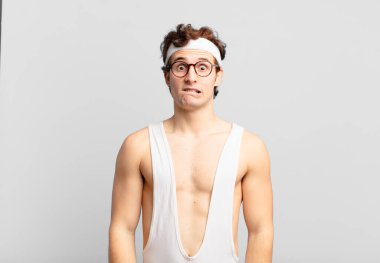 humorous sport man looking puzzled and confused, biting lip with a nervous gesture, not knowing the answer to the problem