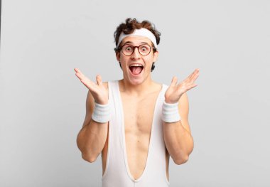 humorous sport man looking happy and excited, shocked with an unexpected surprise with both hands open next to face