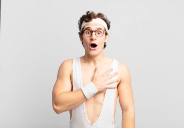 humorous sport man feeling shocked and surprised, smiling, taking hand to heart, happy to be the one or showing gratitude