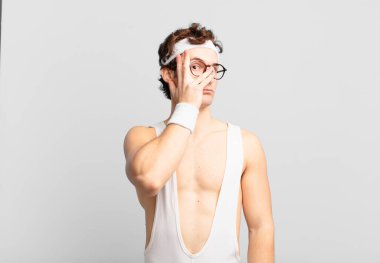 humorous sport man feeling bored, frustrated and sleepy after a tiresome, dull and tedious task, holding face with hand