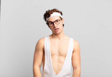 humorous sport man feeling puzzled and confused, with a dumb, stunned expression looking at something unexpected