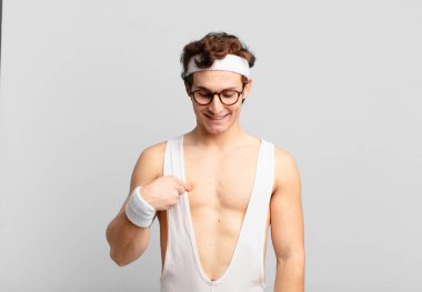 humorous sport man smiling cheerfully and casually, looking downwards and pointing to chest