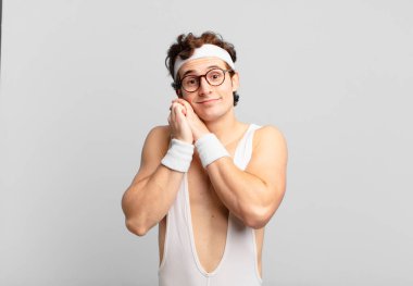 humorous sport man feeling in love and looking cute, adorable and happy, smiling romantically with hands next to face