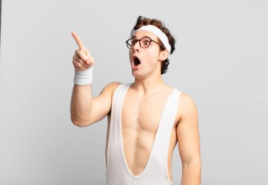 humorous sport man feeling shocked and surprised, pointing and looking upwards in awe with amazed, open-mouthed look