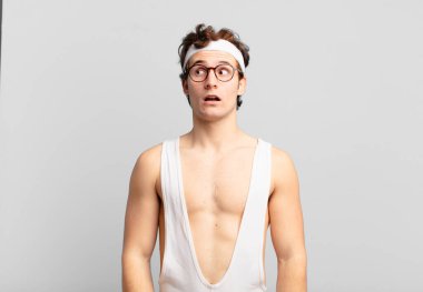 humorous sport man feeling shocked, happy, amazed and surprised, looking to the side with open mouth