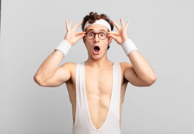 humorous sport man feeling shocked, amazed and surprised, holding glasses with astonished, disbelieving look