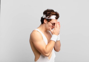 humorous sport man covering eyes with hands with a sad, frustrated look of despair, crying, side view