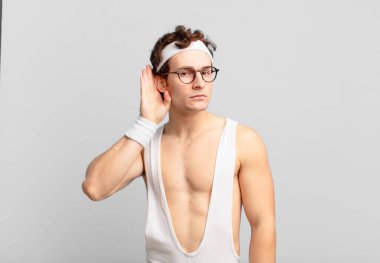 humorous sport man looking serious and curious, listening, trying to hear a secret conversation or gossip, eavesdropping