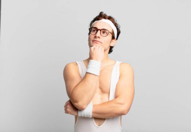 humorous sport man feeling thoughtful, wondering or imagining ideas, daydreaming and looking up to copy space