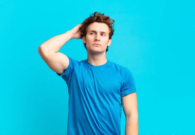 young sport boy feeling puzzled and confused, scratching head and looking to the side