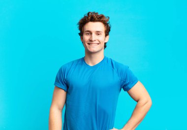 young sport boy smiling happily with a hand on hip and confident, positive, proud and friendly attitude