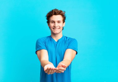 young sport boy smiling happily with friendly, confident, positive look, offering and showing an object or concept