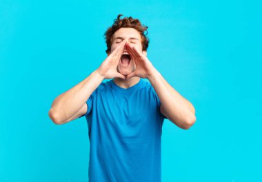 young sport boy feeling happy, excited and positive, giving a big shout out with hands next to mouth, calling out