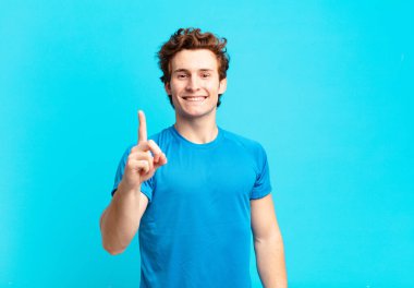 Genç sporcu çocuk gülümsüyor ve arkadaş canlısı görünüyor, bir numara ya da ilk eli önde, geriye doğru sayıyor.