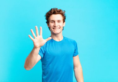 Genç sporcu çocuk gülümsüyor ve arkadaş canlısı görünüyor, 5 ya da 5 numarayı gösteriyor, elleri önde, geriye doğru sayıyor.