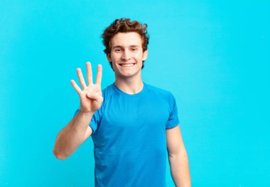 Genç sporcu çocuk gülümsüyor ve arkadaş canlısı görünüyor. Elleri önde, geriye doğru sayıyor.