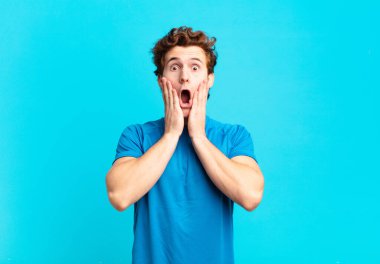 Genç sporcu çocuk şok olmuş ve korkmuş hissediyor, ağzı açık ve elleri yanaklarında korkmuş görünüyor.